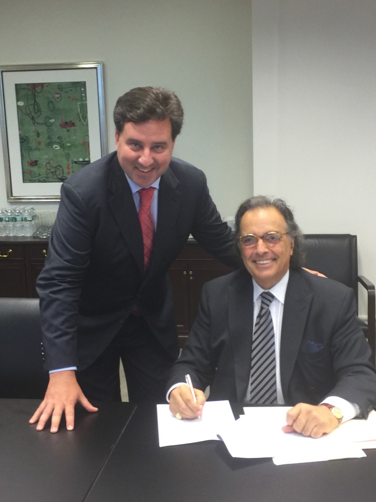 Carlo Mantica, left, and Steve Acunto, right, signing the purchase of a larger building for La Scuola.