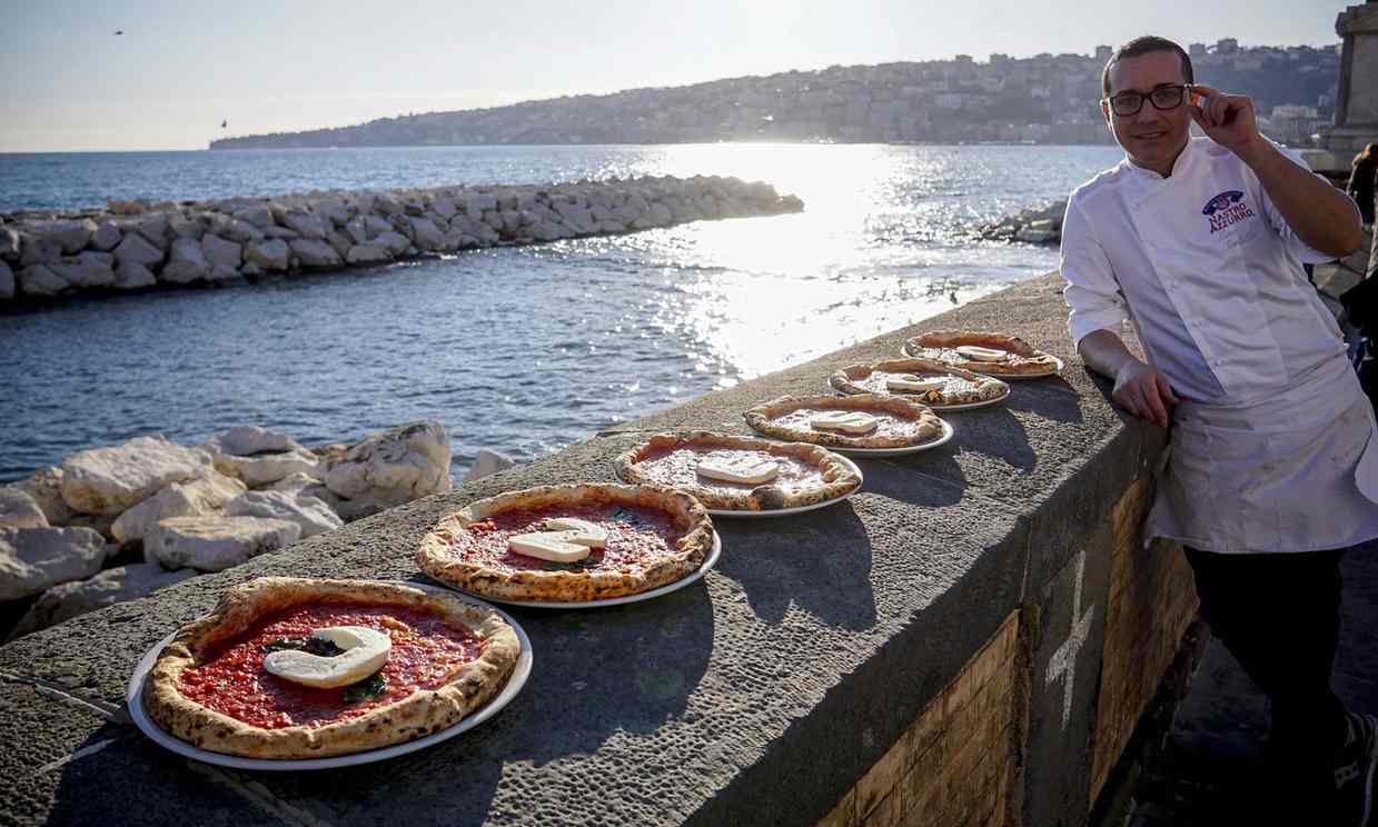Gino Sorbillo poses with Neapolitan pizza with Unesco atop. Photo courtesy of The Guardian.